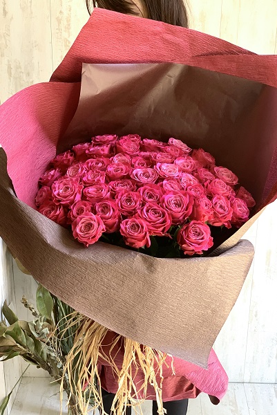 鮮やかな色合いが目を引く、濃いピンクのバラの花束(50本前後)