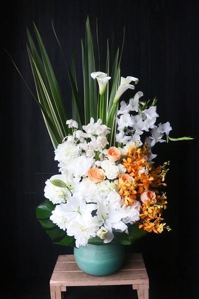 白いお花に挿し色でオレンジ色を取り入れたお洒落なアレンジメント花