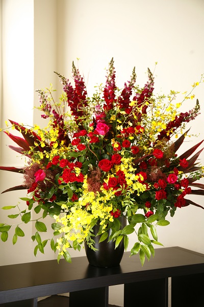 赤と黄色でお祝いの場を華やかに彩る高級アレンジメント花